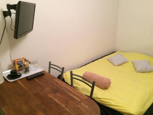Cette chambre comprend une table et un lit jaune. dans l'établissement Studio Cosy, à Paris