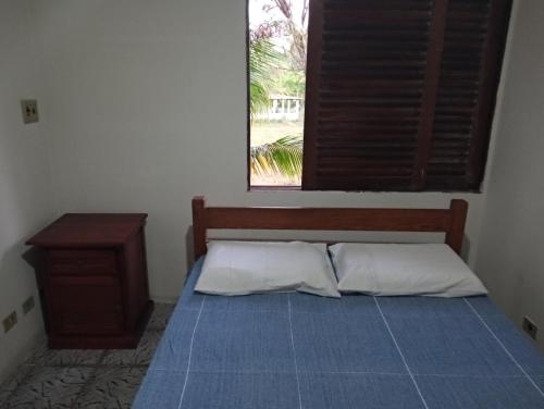 a bed with a blue blanket and a window at Recanto a ver o Mar in Sirinhaém