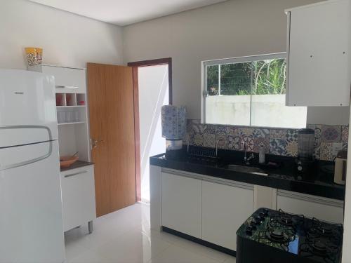 een witte keuken met een wastafel en een raam bij Casa com piscina em c vermelha in Porto Seguro