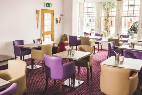 uma sala de jantar com mesas e cadeiras roxas em The Queensgate Hotel em Peterborough