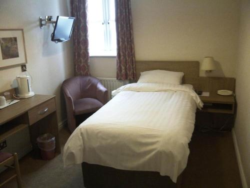 a hotel room with a bed and a chair at The Queensgate Hotel in Peterborough