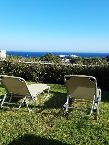 two lawn chairs sitting in the grass near the ocean at Petroto Villas in Kiotari