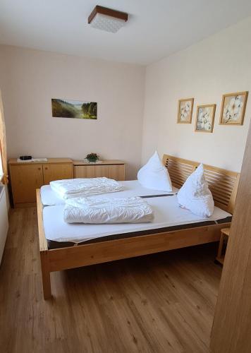 um quarto com uma cama com lençóis brancos e almofadas em Ferienwohnung E. Storm em Kellenhusen