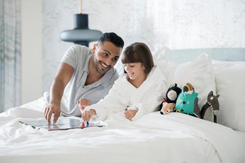a man and woman laying in bed looking at a book at Four Seasons Resort Dubai at Jumeirah Beach in Dubai