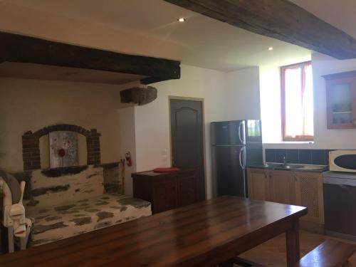 a kitchen with a wooden table and a refrigerator at Gite a la ferme in Rouessé-Vassé