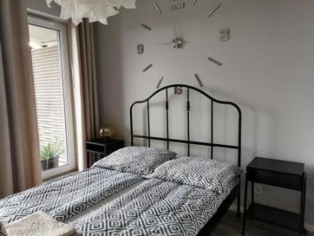 ein Schlafzimmer mit einem Bett mit einer Uhr an der Wand in der Unterkunft Apartament przy Aquaparku w Redzie in Rumia
