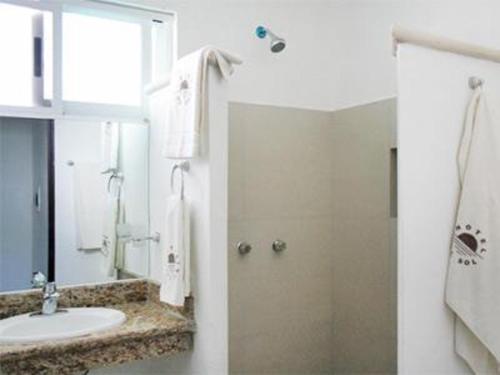 a white bathroom with a sink and a shower at Hotel Del Sol in Cancún