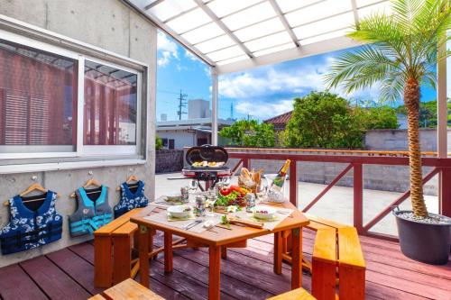 a dining table on a deck with a palm tree at Cozy in Nago