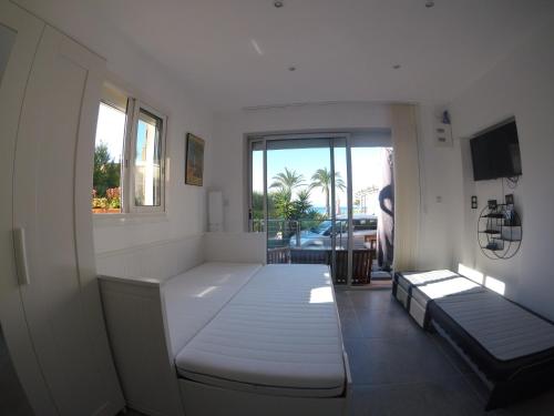 Cette chambre blanche dispose de deux lits et d'une fenêtre. dans l'établissement Sanarybeach, à Sanary-sur-Mer