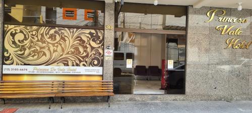 un front de magasin avec un banc en bois devant une fenêtre dans l'établissement Princesa do Vale Hotel, à Aparecida