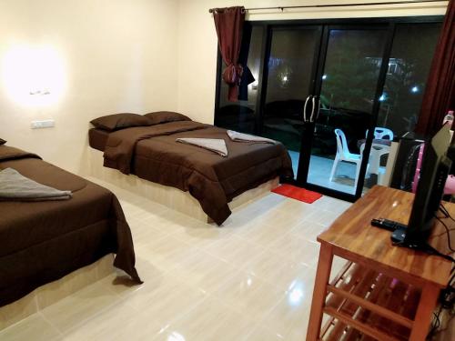 a bedroom with two beds and a tv and a window at เฟรนด์แคมป์ in Khao Kho