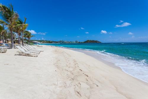 a sandy beach with lounge chairs and the ocean at Princess Heights Luxury Condo Hotel in Dawn Beach