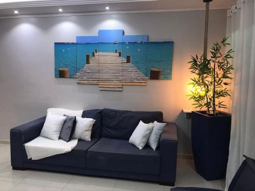 una sala de estar con un sofá azul y una pintura de muelle en Apartamento com Clube e Vista para o Lago, en Cabo Frío