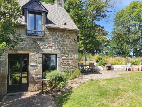 a stone house with a table and chairs in a yard at Le Grand Domaine du Rocher in Bonnemain