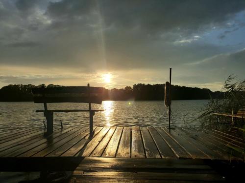 a bench sitting on a dock in front of a lake at Mazurska Chata Czepiela in Langendorf
