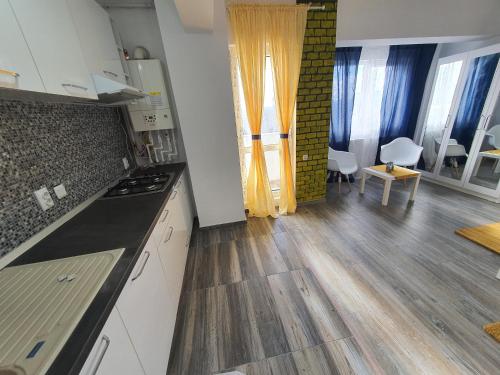 uma cozinha com armários brancos e piso em madeira em Garsoniera Argedava em Bucareste