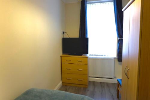 a bedroom with a television on a dresser with a window at Milburn Cottage 2- Luxury Accommodation in Monkwearmouth