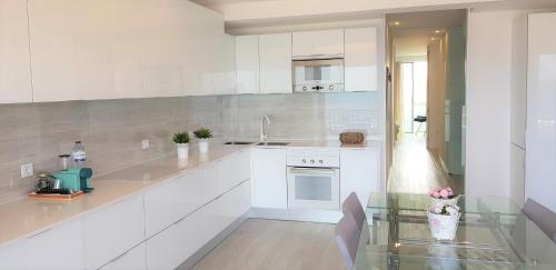 a kitchen with white cabinets and a glass table at Avenida dos Banhos Apartment in Póvoa de Varzim