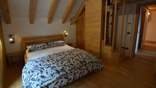 een slaapkamer met een bed met een blauw en wit dekbed bij Chalet Corone Monte Zoncolan in Sùtrio