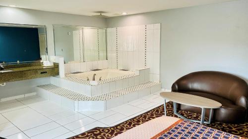 y baño con bañera, silla y mesa. en Moonlight Inn and Suites en Houston