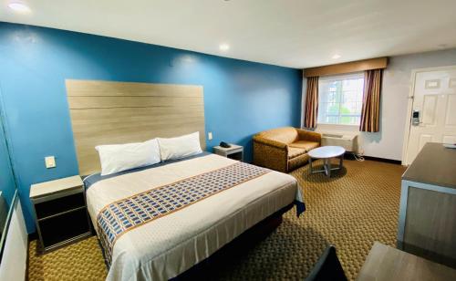 Habitación de hotel con cama y silla en Moonlight Inn and Suites, en Houston