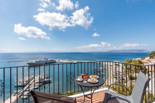 a balcony with a table and chairs and the ocean at Servani Studios & Suites in Loutraki