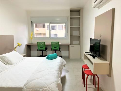 um quarto com uma cama e uma secretária com 2 cadeiras verdes em Apartamento impecável FM - RETIRADA DAS CHAVES MEDIANTE AGENDAMENTO COM UMA HORA DE ANTECEDÊNCIA COM ANDREIA OU LUIS em Porto Alegre