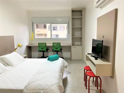 a bedroom with a bed and a desk with two green chairs at Apartamento impecável FM - RETIRADA DAS CHAVES MEDIANTE AGENDAMENTO COM UMA HORA DE ANTECEDÊNCIA COM ANDREIA OU LUIS in Porto Alegre