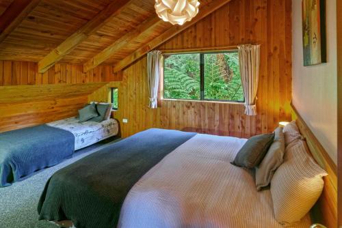 a bedroom with two beds in a log cabin at Buena Vista Apartment in Marahau