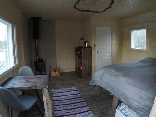 a bedroom with a bed and a table and windows at Aurora Husky Hut in Inari