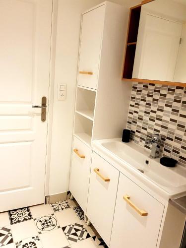 - une cuisine avec des placards blancs et du carrelage noir et blanc dans l'établissement Gîte de Beg Menez Le 26 - Gîte à La Forêt-Fouesnant, à La Forêt-Fouesnant