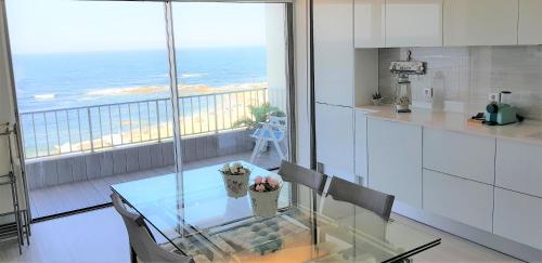 a kitchen with a glass table and a view of the ocean at Avenida dos Banhos Apartment in Póvoa de Varzim