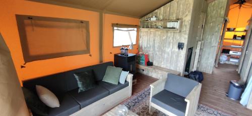 sala de estar con sofá negro y pared de color naranja en Le Relais d'Artagnan - relais équestre, en Mortier