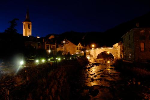 a city at night with a bridge and a clock tower at Hotel Vall d´Aneu in Esterri d'Àneu