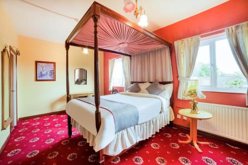 a bedroom with a canopy bed and a red carpet at OYO The Royal Hotel in Newcastle upon Tyne