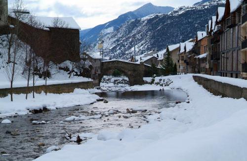 a river covered in snow in a town with buildings at Hotel Vall d´Aneu in Esterri d'Àneu