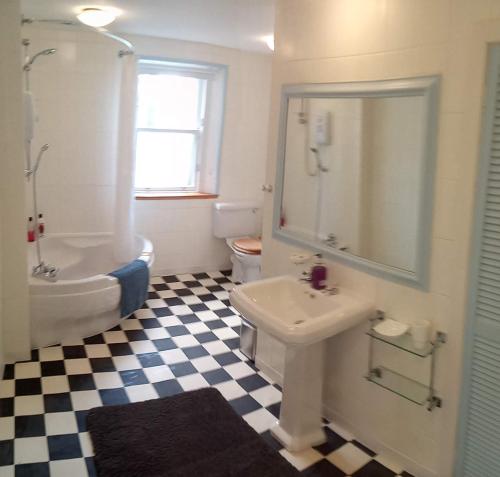 a bathroom with a sink and a tub and a toilet at Kirkview House in Moffat