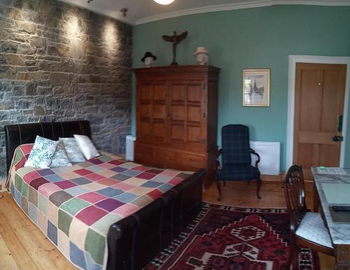 a bedroom with a bed and a stone wall at Kirkview House in Moffat