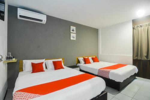 a hotel room with two beds with orange and white sheets at Super OYO 89465 Golden Lounge in Kuching