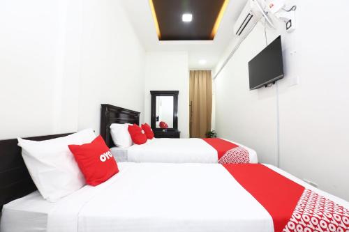 2 camas con almohadas rojas y blancas en una habitación en Super OYO 89678 Ady Hotel, en Kuala Terengganu