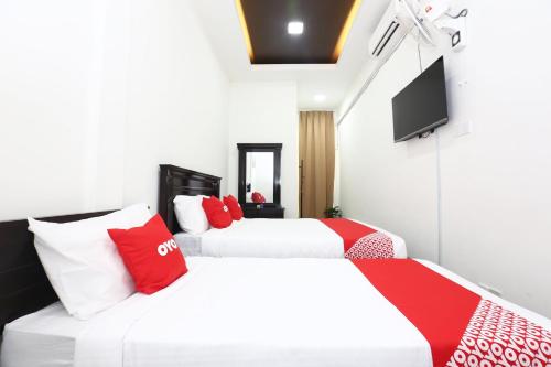 2 łóżka z białymi i czerwonymi poduszkami w pokoju w obiekcie Super OYO 89678 Ady Hotel w mieście Kuala Terengganu