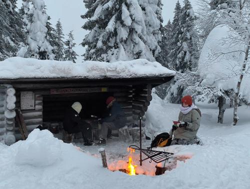 a group of people sitting around a fire in the snow at Ylämaja - with a stunning view in Ruka