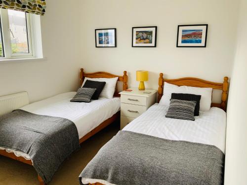 um quarto com 2 camas e um candeeiro numa mesa de cabeceira em Furzy House em Pembrokeshire