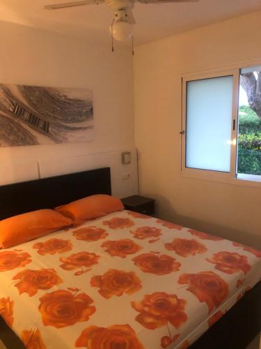 a bedroom with a bed with orange pillows and a window at Los tunos campo internacional in Maspalomas