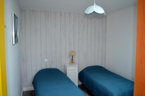 een slaapkamer met 2 blauwe bedden en een nachtkastje bij Maison de caractère proche des Sables d’Olonne in Talmont
