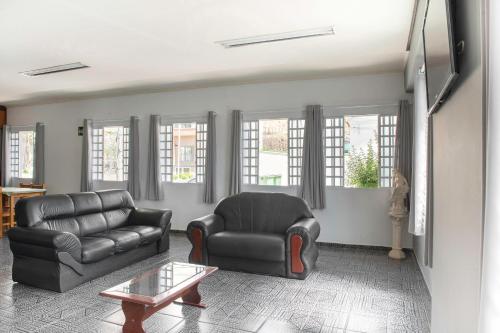 a living room with a leather couch and a chair at Hotel dos Nobres in Poços de Caldas