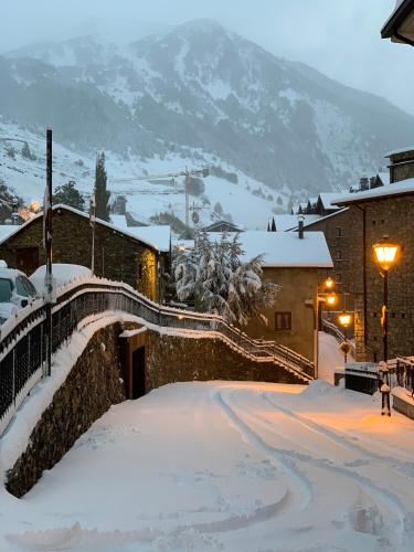a snow covered street in a town with a mountain at Hôtel Bruxelles in Soldeu