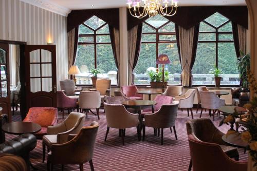 a hotel lobby with tables and chairs and windows at Oakwood Hall Hotel in Bingley