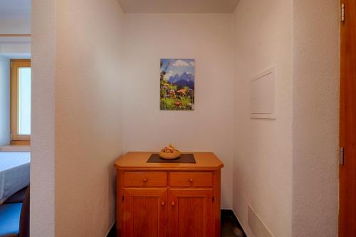 a bedroom with a wooden cabinet and a painting on the wall at Apartments Kaserott in Villnoss
