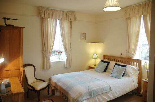a bedroom with a bed and a chair and a window at Newcourt Barton in Cullompton